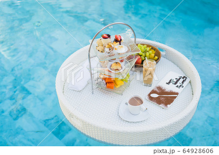 Breakfast and afternoon tea set floating around swimming pool Breakfast and afternoon tea set floating around swimming pool 64928606