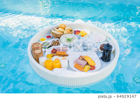 Floating breakfast set in tray with fried egg omelette sausage ham bread fruit milk juice coffee 64929147