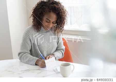 Woman writing in card at table 64930331