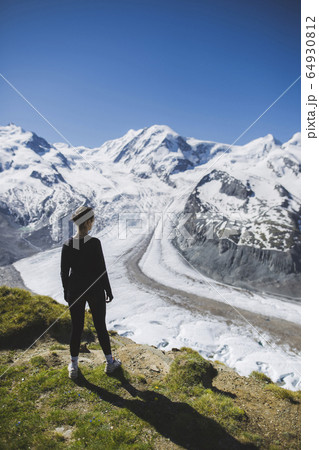 Woman standing on grass by Gorner Glacier in Valais, Switzerland Woman standing on grass by Gorner Glacier in Valais, Switzerland 64930812