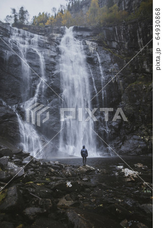Man standing by Skjervefossen waterfall in Norway Man standing by Skjervefossen waterfall in Norway 64930868
