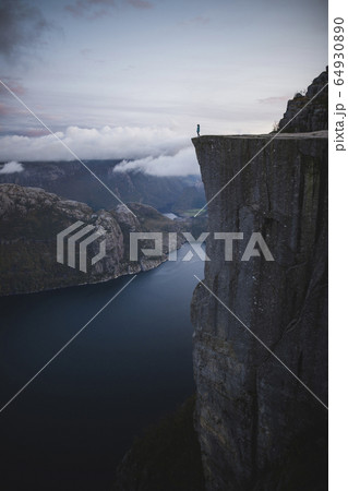 Person standing on Preikestolen cliff in Rogaland, Norway 64930890