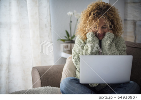Smiling woman working with laptop on sofa Smiling woman working with laptop on sofa 64930907