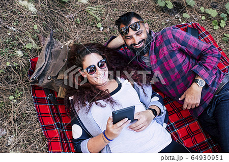 Smiling couple lying on blanket using tablet 64930951