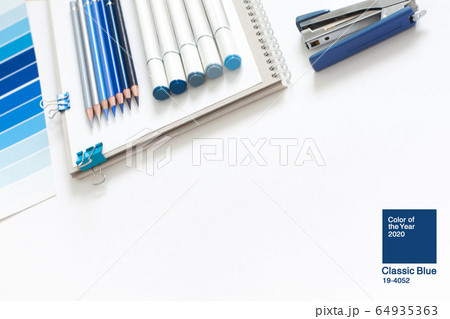 Classic Blue. Color of the Year 2020. Top view of workspace with white notebook, color palette, fabric sample and copy space. Flatlay minimalism. 64935363