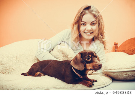 Woman with dog waking up in bed after sleeping. Woman with dog waking up in bed after sleeping. 64938338