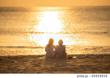 Couple in love watching sunset together on beach travel summer holidays.  64938938