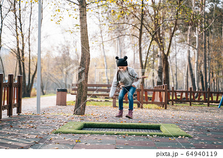 Happy school girl jumping on a small trampoline in the park Happy school girl jumping on a small trampoline in the park 64940119
