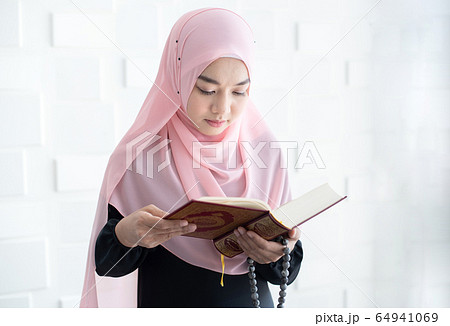 Beautiful young asian muslim woman reading quran Beautiful young asian muslim woman reading quran 64941069