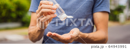 Man in a small town in a medical mask uses a sanitizer because of a coronovirus epidemic BANNER Man in a small town in a medical mask uses a sanitizer because of a coronovirus epidemic BANNER 64943991