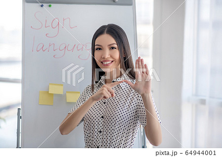 Young sign language interpreter pointing to her thumb 64944001