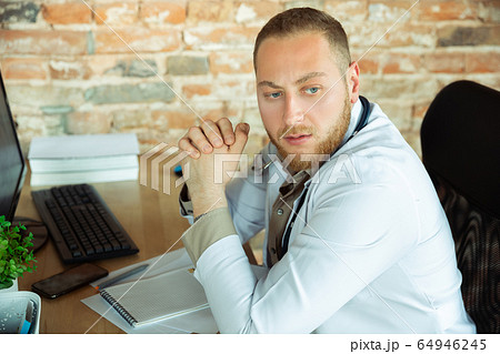 Caucasian doctor resting after consulting for patient, working in cabinet 64946245