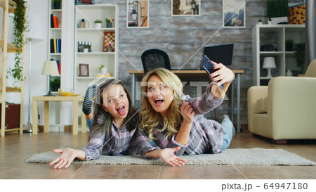 Mother and daughter lying on the floor 64947180