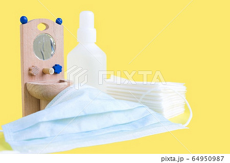 Wooden toy washbasin and anti-bacterial disinfectants in white vials on yellow. Concept personal hygiene during pandemic coronavirus. Frequent and thorough hand washing 64950987