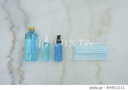 Blue Ethyl Alcohol spray bottle, Alcohol gel bottle, Alcohol in plastic bottle and blue surgical masks on the marble desk. Coronavirus Protection Set. Blue Ethyl Alcohol spray bottle, Alcohol gel bottle, Alcohol in plastic bottle and blue surgical masks on the marble desk. Coronavirus Protection Set. 64951211