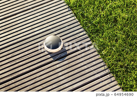 Round black outdoor lighting on a light brown jetty. 64954690