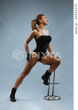 Portrait of a beautiful red-haired, woman in the studio, sitting on the bar counter body shirt. Fashion shooting, gray background. Portrait of a beautiful red-haired, woman in the studio, sitting on the bar counter body shirt. Fashion shooting, gray background. 64956170