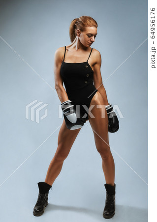 Beautiful woman with black boxing gloves on a gray background. Copy space, sport banner, hard work on yourself and your body. 64956176