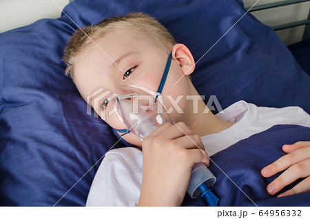 Sick boy breathing through nebulizer, inhaler for treatment prevention. Coronavirus, asthma and allergies. 64956332