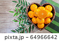 tangerines in heart shaped basket and green leaves 64966642