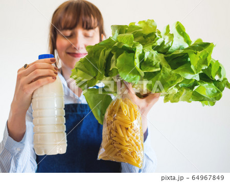 Woman in blue apron with food staples in hand Woman in blue apron with food staples in hand 64967849