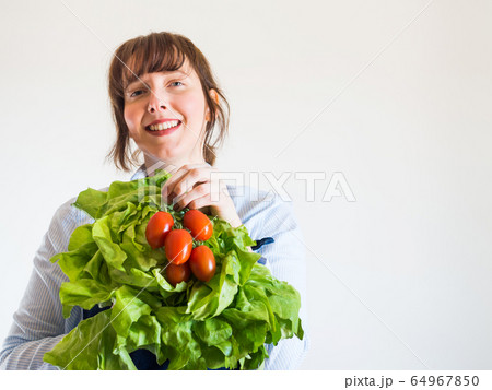 Woman in blue apron with fresh produce in hand Woman in blue apron with fresh produce in hand 64967850