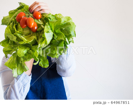 Woman in blue apron with fresh produce in hand Woman in blue apron with fresh produce in hand 64967851