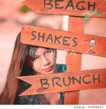 Asian Tanned skin woman is hiding behind Beach 64968023