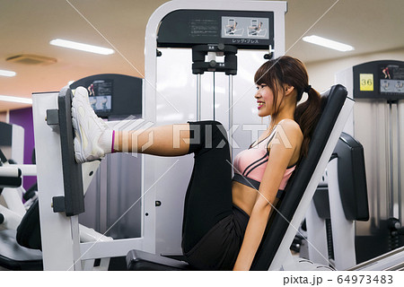 スポーツジムでトレーニングをする若い女性 スポーツジムでトレーニングをする若い女性 64973483