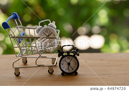 Fast delivery, time value of money concept : white analog clock in a blue - silver shopping cart or a supermarket shopping basket on wooden table. depicts the importance of time in our daily life. Fast delivery, time value of money concept : white analog clock in a blue - silver shopping cart or a supermarket shopping basket on wooden table. depicts the importance of time in our daily life. 64974720