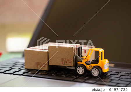 Logistic and cargo freight concept: Fork-lift a truck moves a paper box on notebook keyboard. depicts International freight or shipping service for online shopping. 64974722