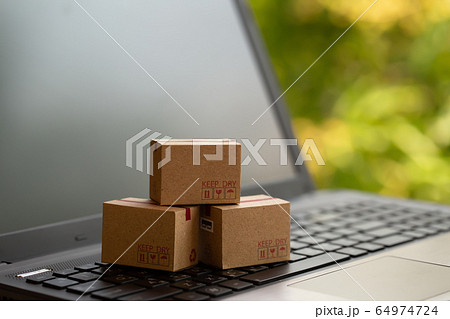 Online shopping, ecommerce and delivery service concept: Paper cartons or boxes on notebook keyboard. depicts modern or trendy customers always order things from retailer sites over the internet. 64974724