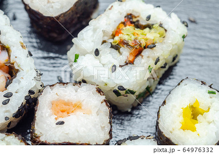 Mix veggie sushi and fish sushi on the black stone Mix veggie sushi and fish sushi on the black stone 64976332