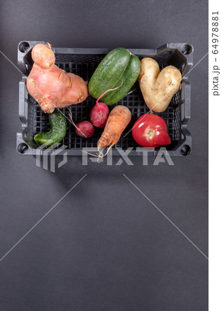 Fresh ripe ugly vegetables in plastic box on dark grey background. Waste zero concept. Top view, copy space. Fresh ripe ugly vegetables in plastic box on dark grey background. Waste zero concept. Top view, copy space. 64978881