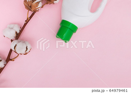 Liquid washing detergent in plastic bottle and cotton flowers on pink background. Liquid washing detergent in plastic bottle and cotton flowers on pink background. 64979461