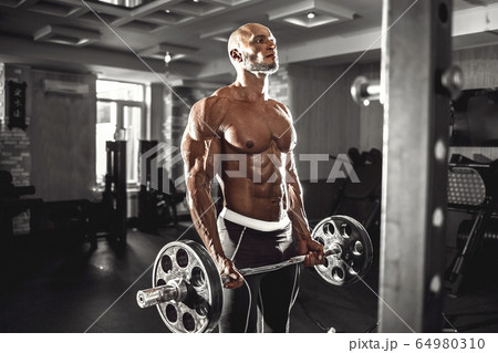 Muscular man working out in gym doing exercises with dumbbells at biceps, strong male naked torso abs Muscular man working out in gym doing exercises with dumbbells at biceps, strong male naked torso abs 64980310