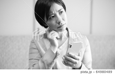 スマホとネガティブな女性イメージ 64980489