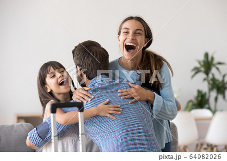 Excited wife and kid hugging father arriving after long trip 64982026