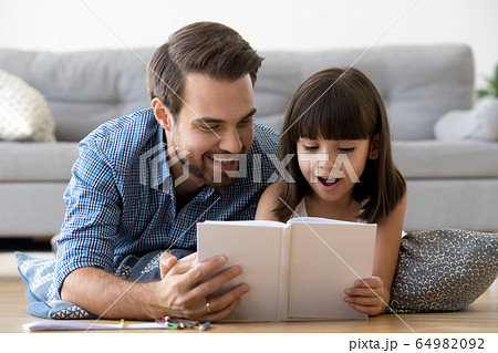 Happy father and surprised kid girl reading book together 64982092