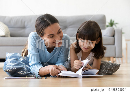Caring mother reading book with little kid girl at home Caring mother reading book with little kid girl at home 64982094