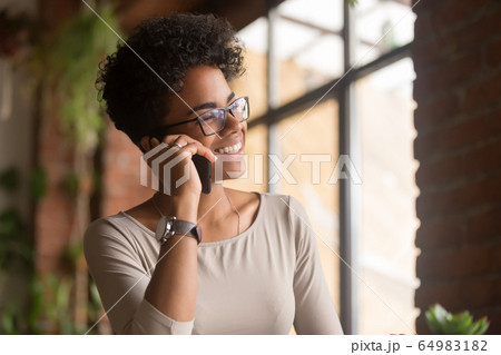 Happy african american young businesswoman talking on phone in office 64983182