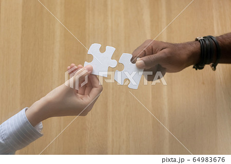 Two diverse male female hands holding join jigsaw puzzle 64983676