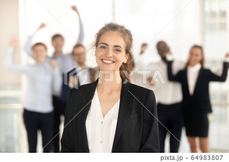 Proud lady leader looking at camera while team celebrating victory 64983807