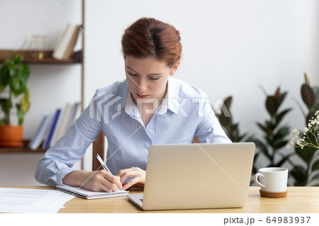Focused millennial business woman office worker make notes planning work 64983937