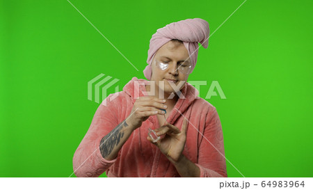 Portrait of transsexual man in bathrobe spraying perfume on neck and wrist 64983964