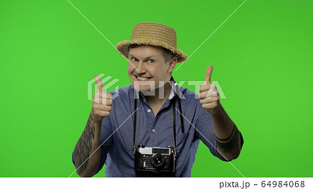Portrait of young man tourist photographer giving thumbs up. Chroma key 64984068