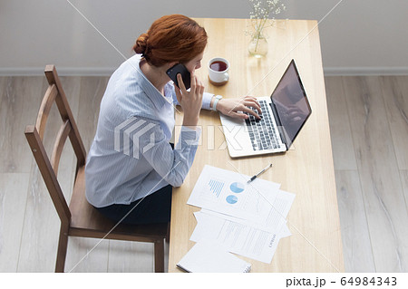 Businesswoman using laptop talking on phone in office, top view 64984343
