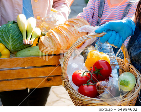 Volunteers in protective gloves hold food packages for the poor during the coronavirus pandemic. Volunteers in protective gloves hold food packages for the poor during the coronavirus pandemic. 64984602