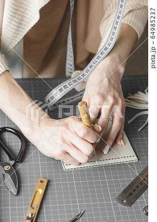 Woman measuring and cutting leather in a workshop 64985237