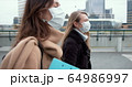 Epidemic control social workers. Two young Caucasian female doctors in face masks walk on city street during quarantine. 64986997